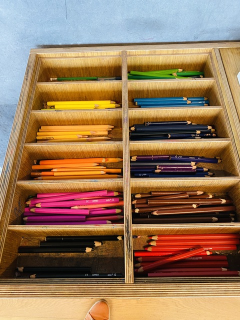 A wooden tray of pencils. 