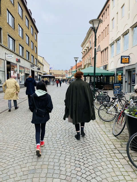 People walking on a cobblestone city street in Sweden. 